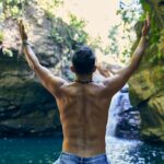 man in blue denim shorts standing near body of water during daytime